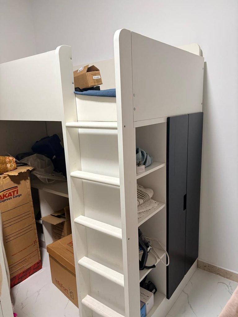A white bunk bed with a ladder and built-in storage shelving in a bedroom. This image supports content about bulky furniture removal, bed removal, and furniture clearance services in Abu Dhabi.